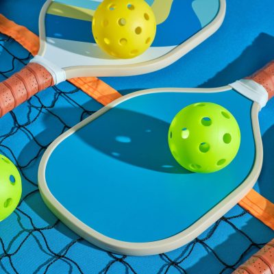 pickleball-paddles-with-balls-on-top-of-a-net-on-a-2023-11-27-05-14-06-utc-min-min